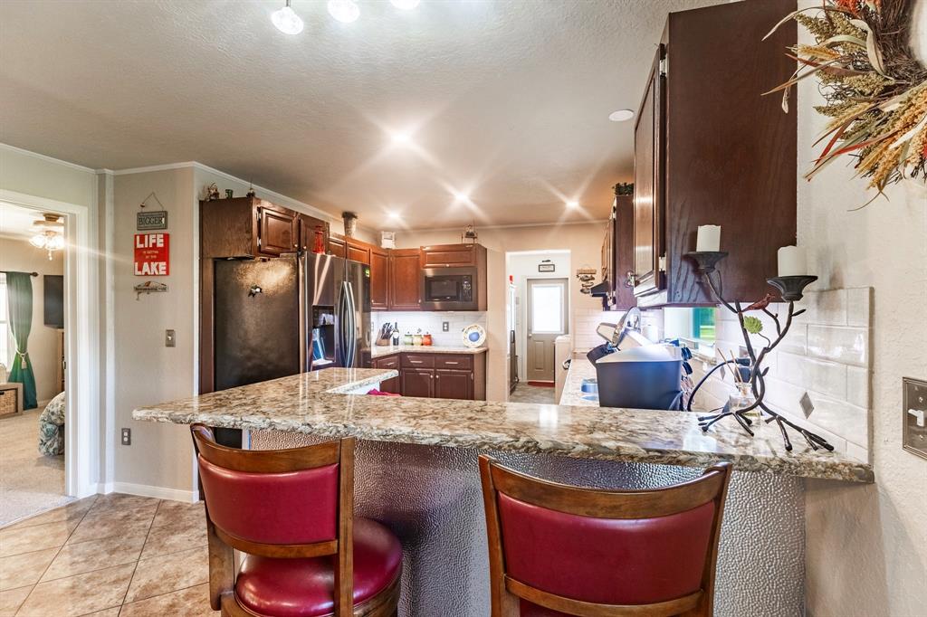 1167 Willow Road Graford, TX 76449 - Photo 14 of 33 a kitchen with granite countertop a sink and refrigerator