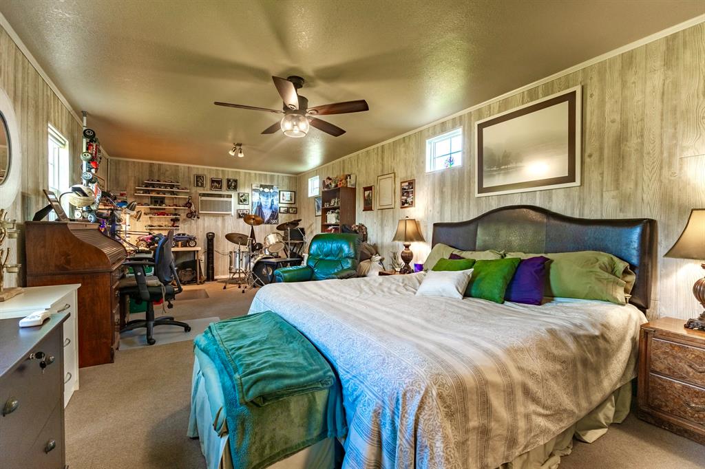 1167 Willow Road Graford, TX 76449 - Photo 23 of 33 a bedroom with a bed a chandelier and flat screen tv