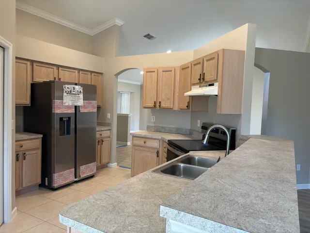 a kitchen with stainless steel appliances granite countertop a refrigerator a stove and a sink