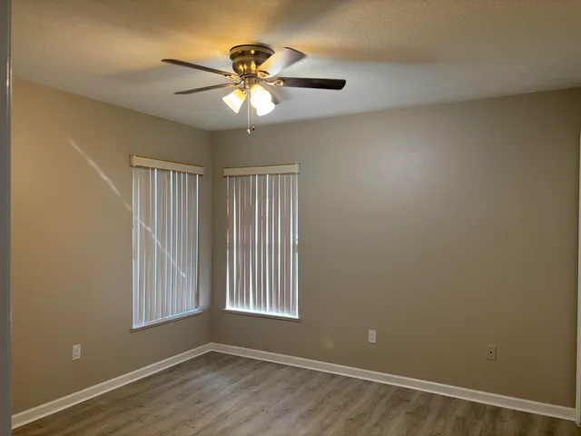 a view of an empty room with a window and wooden floor