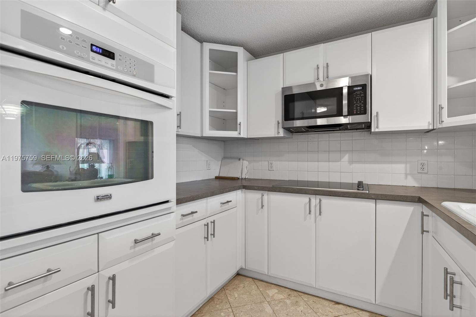 6708 North Pine Island Road Tamarac, FL 33321 - Photo 12 of 40 a kitchen with white cabinets and black appliances