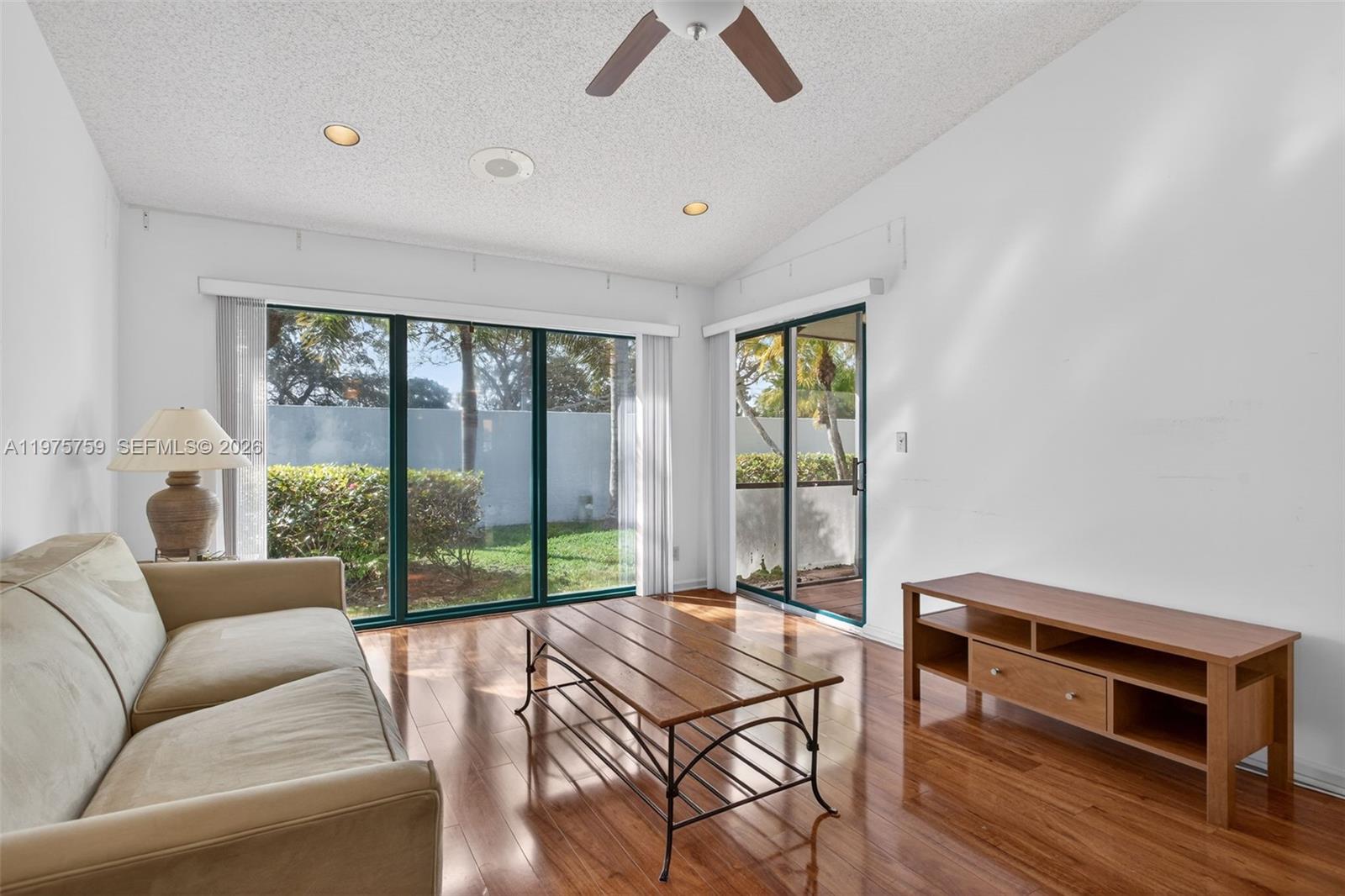 6708 North Pine Island Road Tamarac, FL 33321 - Photo 2 of 40 a living room with furniture a flat screen tv and a floor to ceiling window