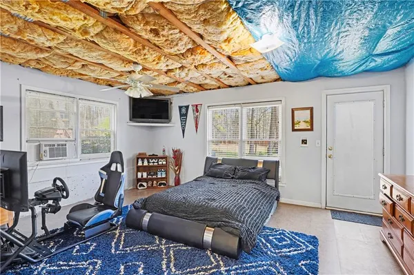 a bedroom with furniture a flat screen tv and a window