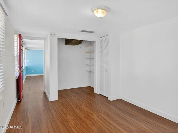 a view of an empty room with wooden floor and a window