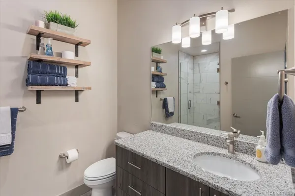 a bathroom with a granite countertop sink a toilet and a mirror