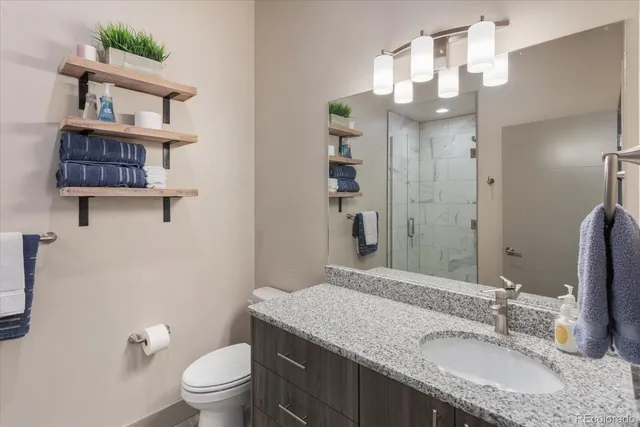 a bathroom with a granite countertop sink a toilet and a mirror