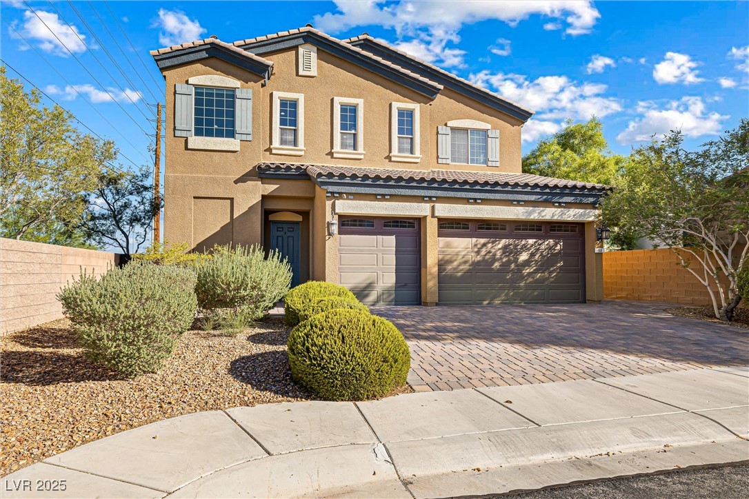 Mediterranean / spanish house with stucco siding, a tile roof, decorative driveway, and a garage