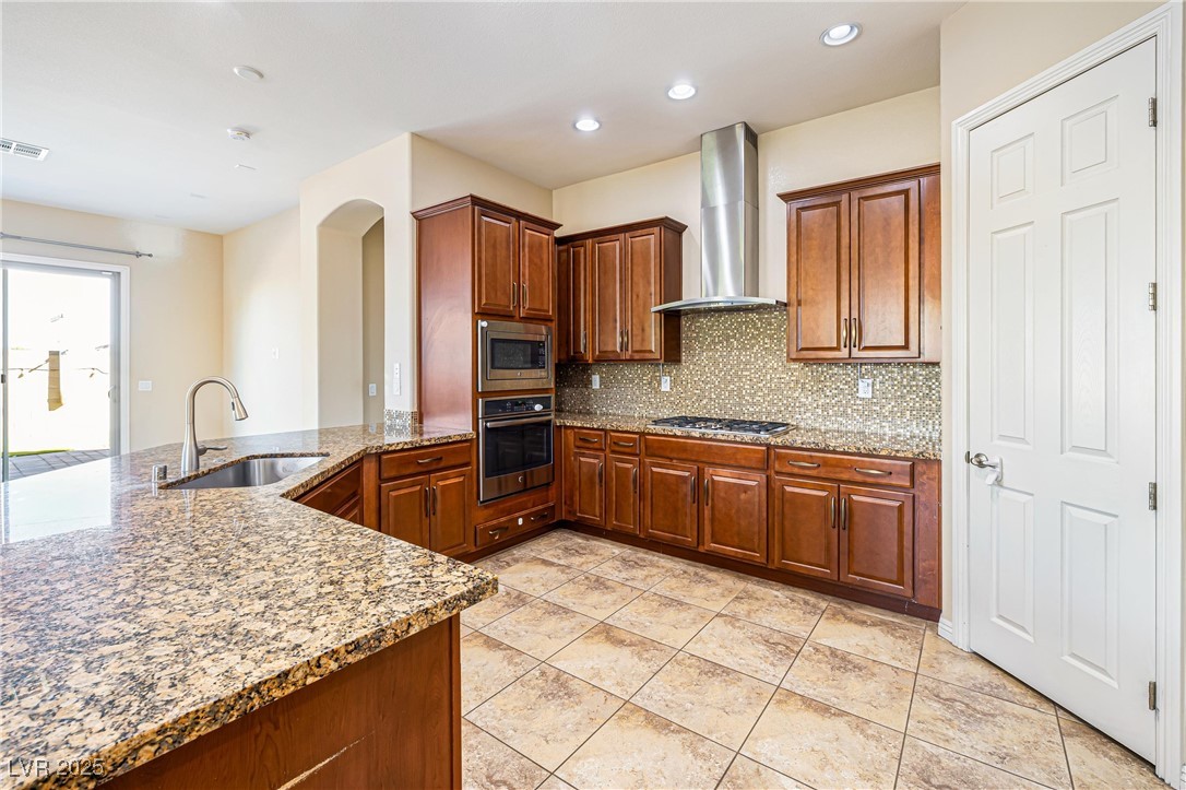 60 Newton Ridge Way Las Vegas, NV 89183 - Photo 10 of 44 Kitchen with light stone countertops, appliances with stainless steel finishes, decorative backsplash, a peninsula, and recessed lighting