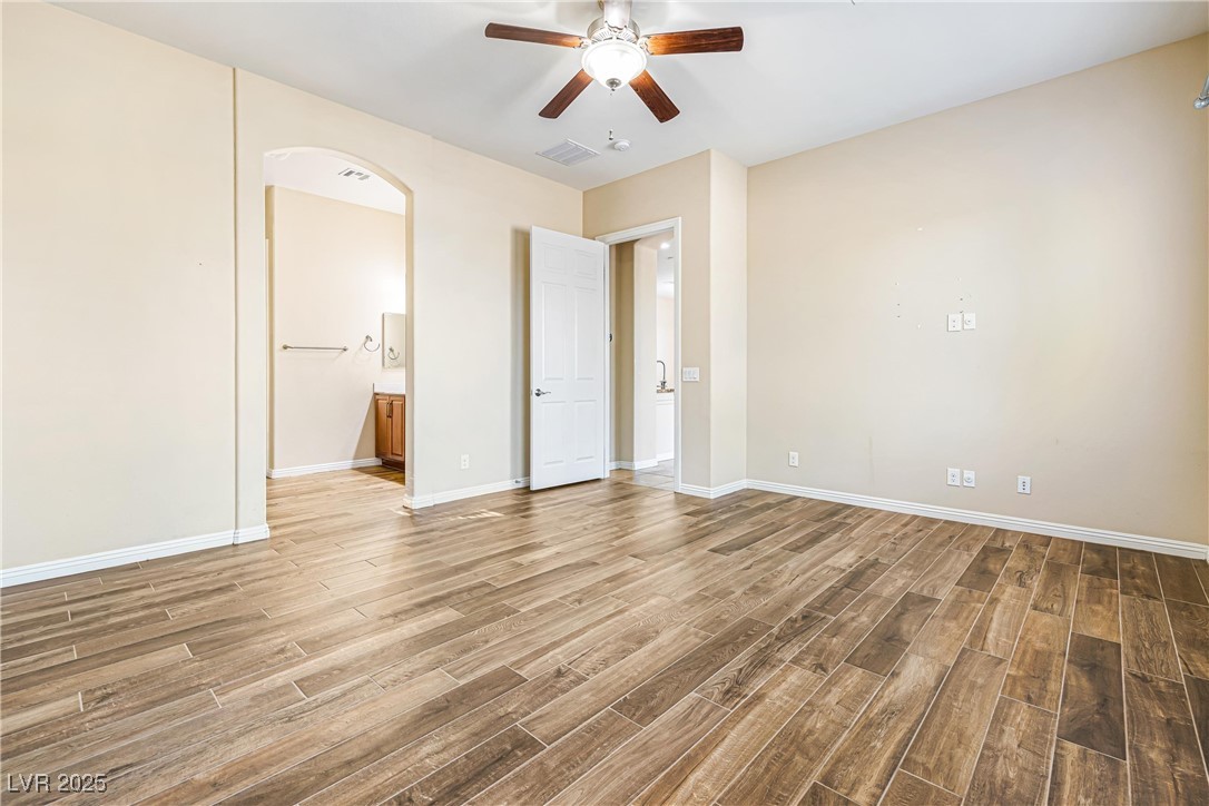 60 Newton Ridge Way Las Vegas, NV 89183 - Photo 15 of 44 Unfurnished bedroom featuring arched walkways, light wood-style floors, ceiling fan, and ensuite bathroom