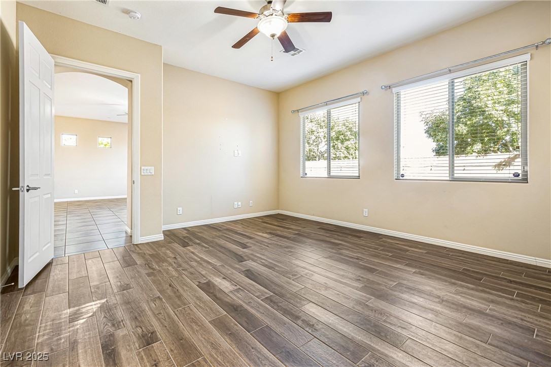 60 Newton Ridge Way Las Vegas, NV 89183 - Photo 16 of 44 Unfurnished room featuring a ceiling fan, healthy amount of natural light, arched walkways, and dark wood finished floors