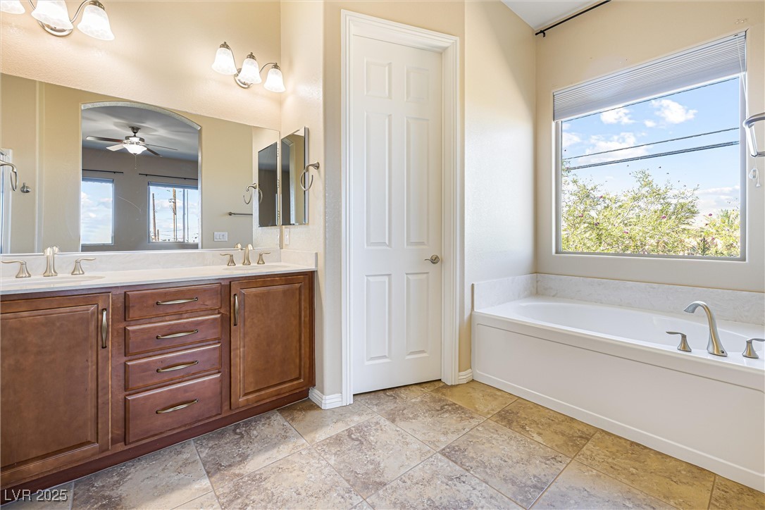 60 Newton Ridge Way Las Vegas, NV 89183 - Photo 17 of 44 Full bathroom with double vanity, plenty of natural light, a garden tub, and a ceiling fan