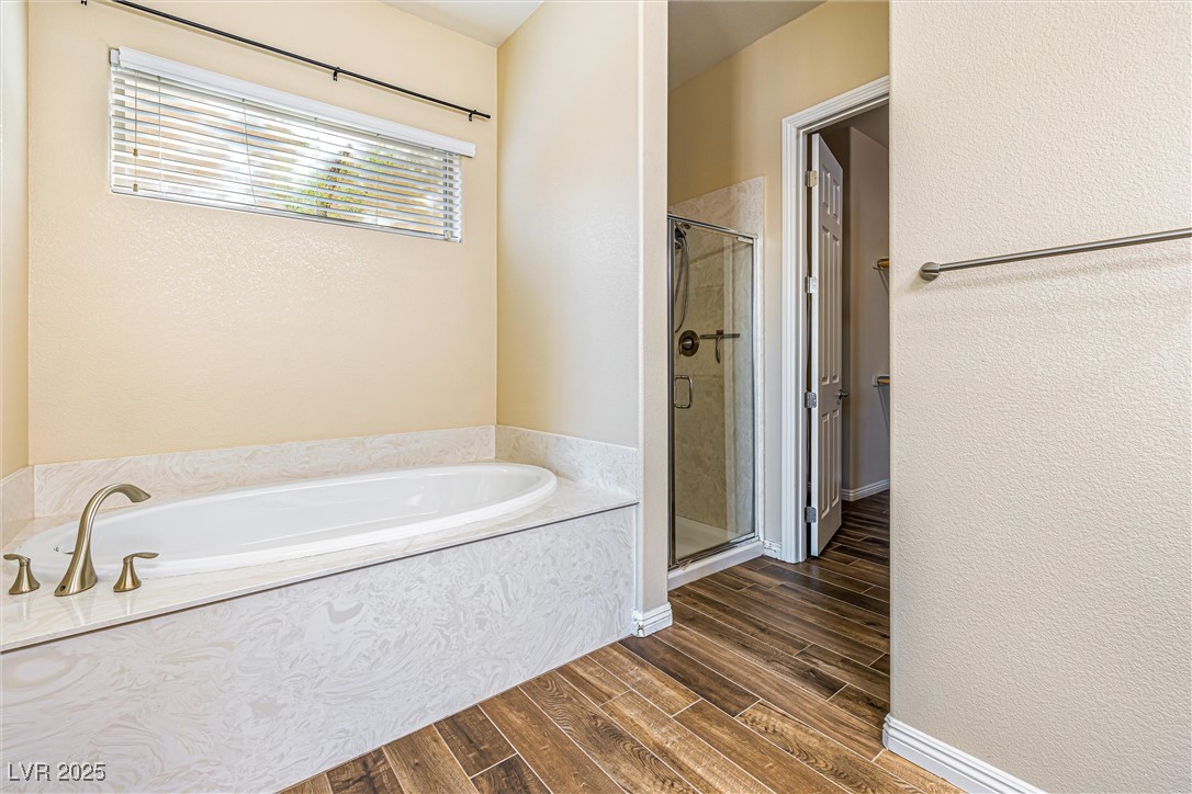 60 Newton Ridge Way Las Vegas, NV 89183 - Photo 19 of 44 Full bathroom with a textured wall, a stall shower, a garden tub, and wood finish floors