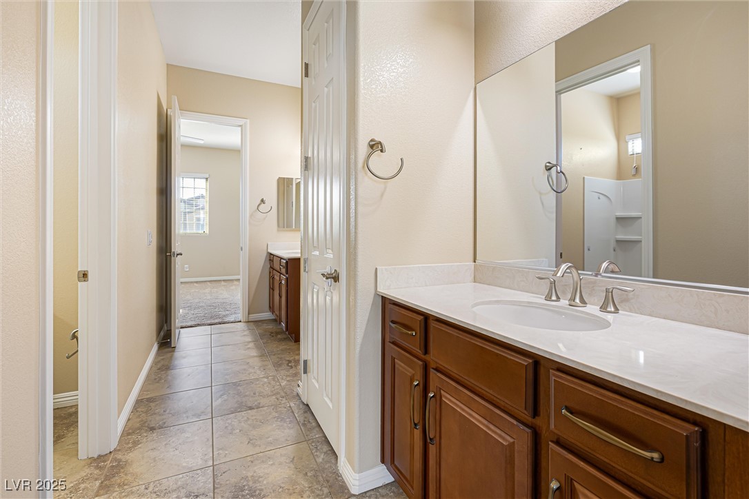 60 Newton Ridge Way Las Vegas, NV 89183 - Photo 25 of 44 Full bathroom featuring vanity, light tile patterned floors, and a textured wall