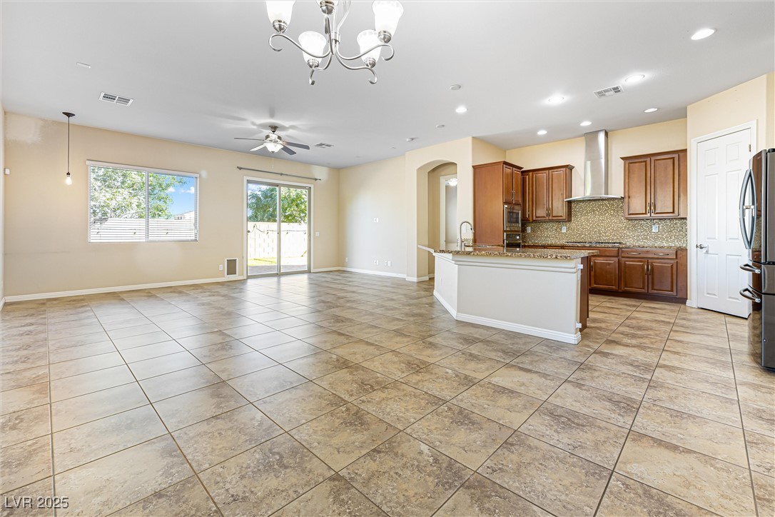 60 Newton Ridge Way Las Vegas, NV 89183 - Photo 44 of 44 Kitchen featuring pendant lighting, backsplash, open floor plan, arched walkways, and brown cabinets