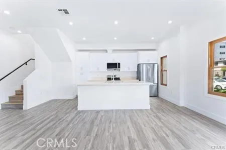 a view of kitchen with stainless steel appliances granite countertop a white stove top oven and a white refrigerator with wooden floors