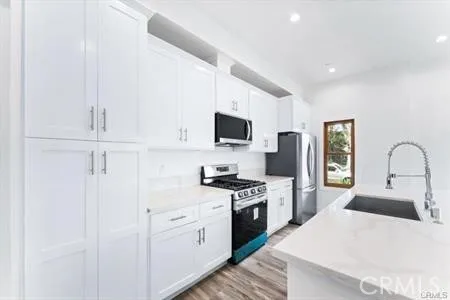 a kitchen with stainless steel appliances granite countertop a stove a sink dishwasher and a refrigerator with wooden floor