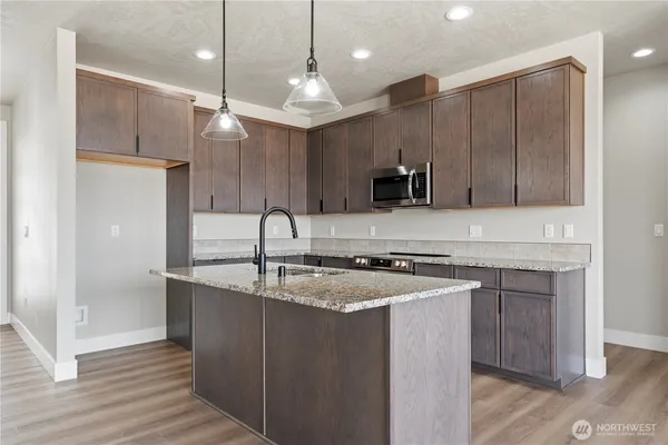 a kitchen with stainless steel appliances granite countertop a sink a stove and a refrigerator