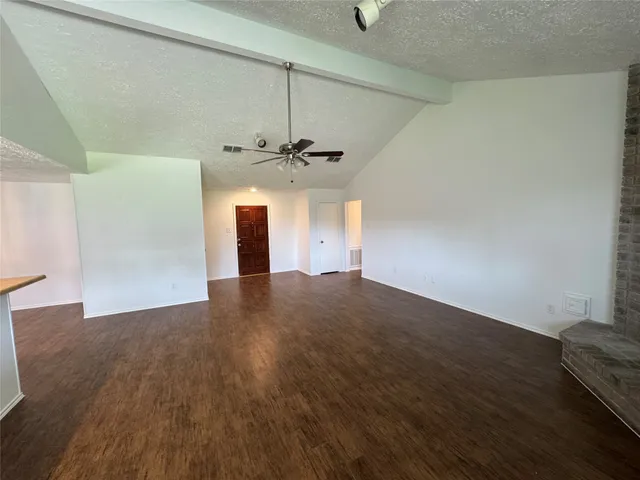 an empty room with wooden floor chandelier fan and windows