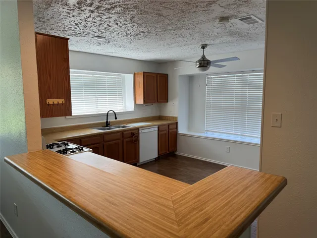 a kitchen with a sink dishwasher and a stove with wooden floor