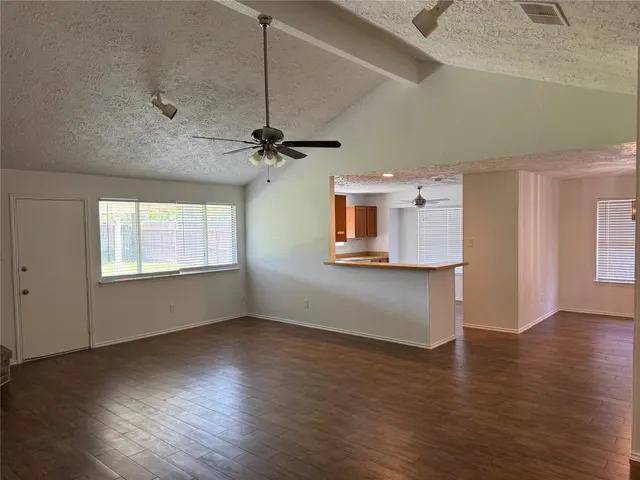 a view of an empty room with a window and wooden floor