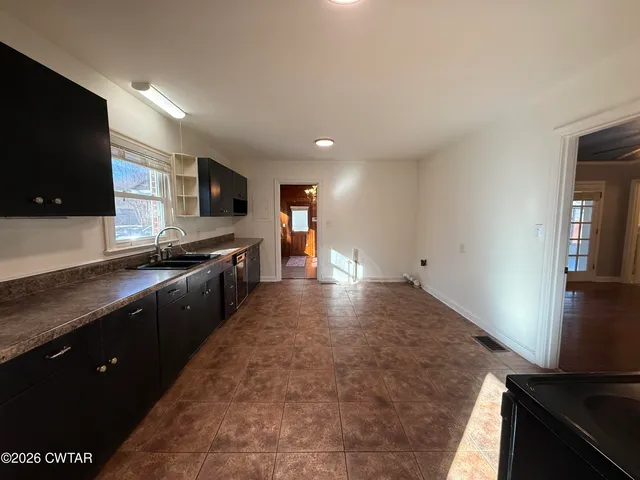 a large kitchen with stainless steel appliances granite countertop a sink a stove and a refrigerator