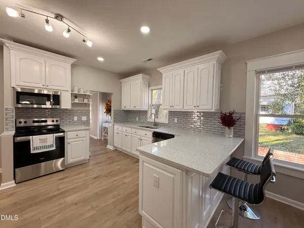 a kitchen with kitchen island granite countertop a stove top oven a sink a counter space and cabinets