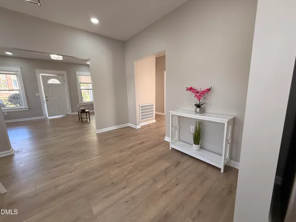 a view of an empty room with wooden floor and a window
