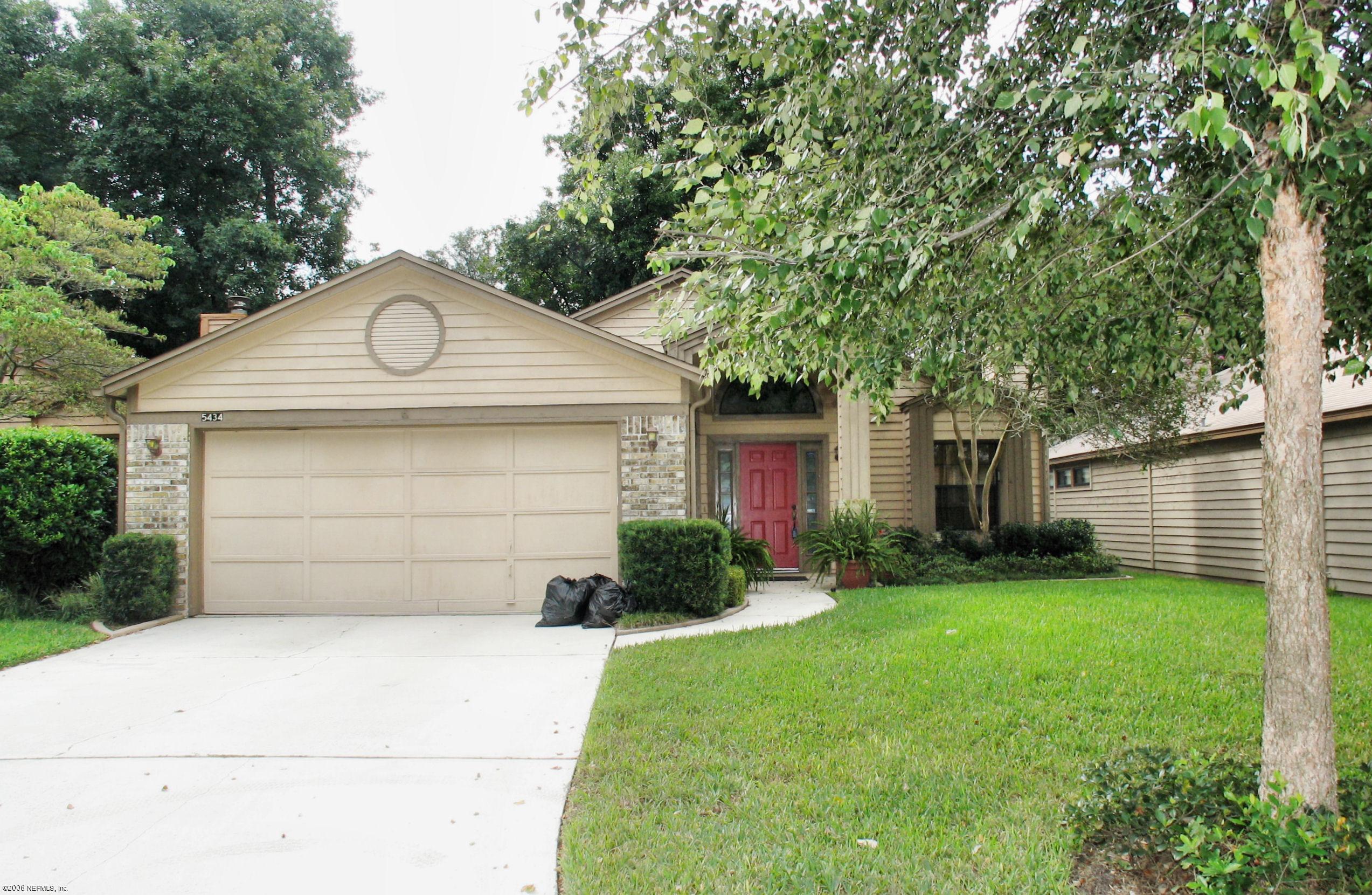 a front view of a house with a garden and trees