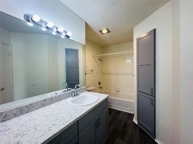 a bathroom with a granite countertop sink a large mirror and a shower