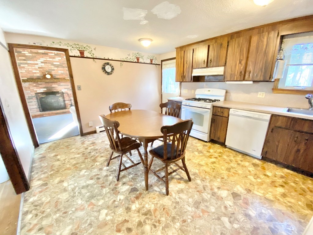1 Pinewood Road Wareham, MA 02532 - Photo 6 of 16 a kitchen with granite countertop a refrigerator a stove a sink and white cabinets with wooden floor