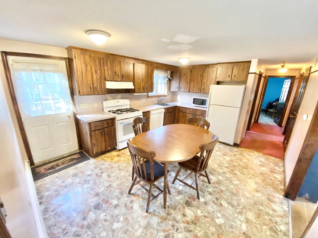 1 Pinewood Road Wareham, MA 02532 - Photo 7 of 16 a kitchen with stainless steel appliances granite countertop a refrigerator a stove a sink a dining table and chairs with wooden floor