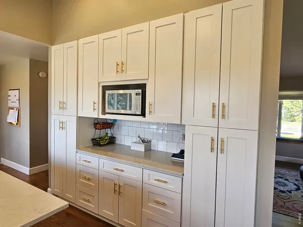 a large white kitchen with kitchen island a large island in the center and stainless steel appliances