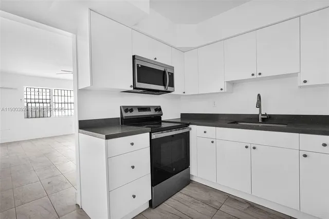 a kitchen with white cabinets and sink