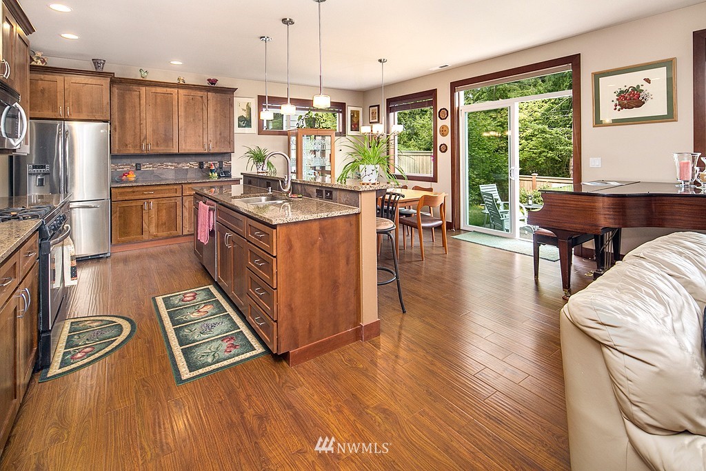 19809 3rd Avenue Southeast Bothell, WA 98012 - Photo 8 of 21 a kitchen with stainless steel appliances granite countertop a refrigerator a stove top oven a dining table and chairs with wooden floor