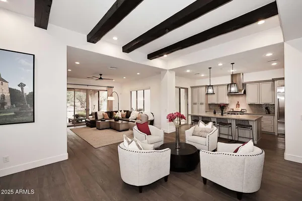 a living room with furniture kitchen area and a wooden floor