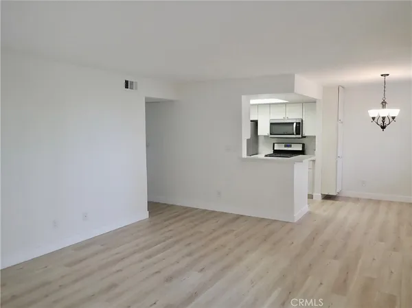 a view of a kitchen with wooden floor electronic appliances and window