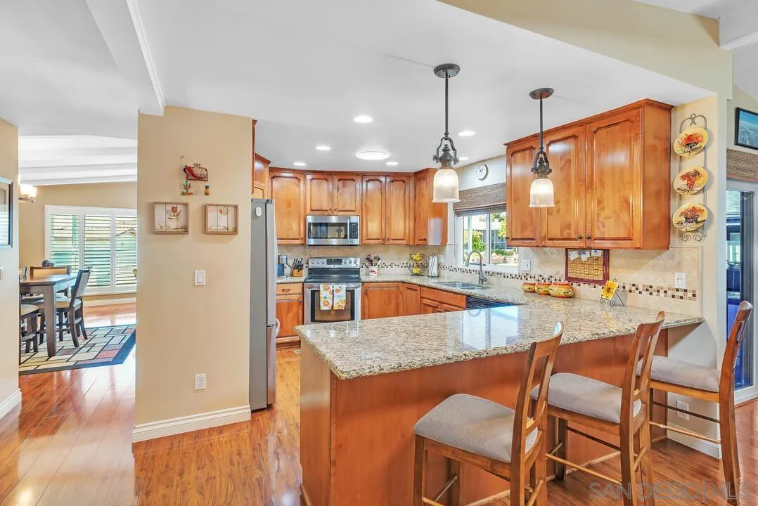 18218 Paradise Mountain Road, Unit 203 Valley Center, CA 92082 - Photo 22 of 68 a kitchen with stainless steel appliances granite countertop a refrigerator a stove top oven and a dining table with wooden floor