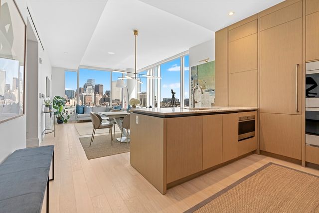 a dining hall with stainless steel appliances kitchen island granite countertop a table chairs refrigerator and microwave