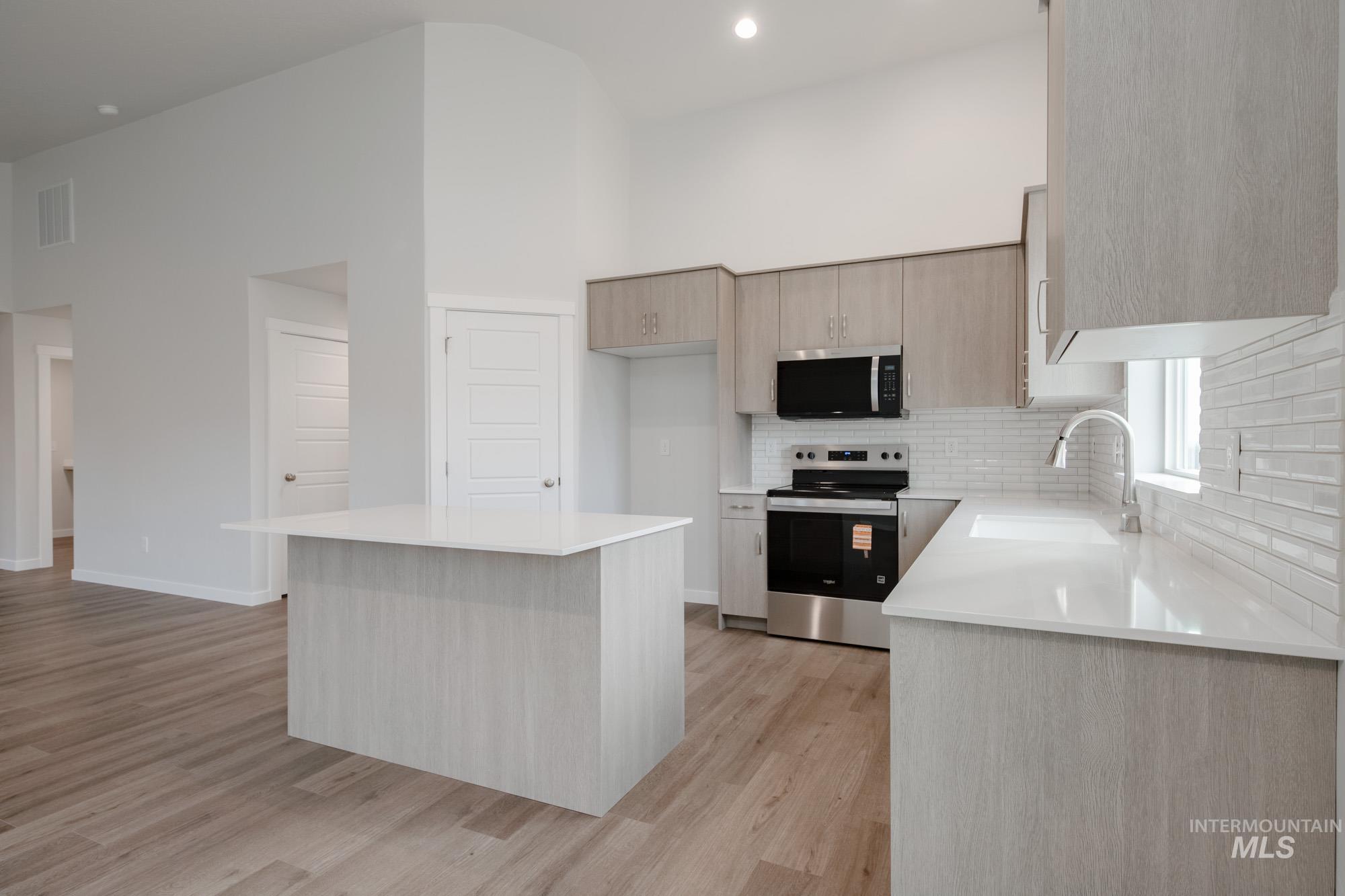 3281 North Waterbrook Way Star, ID 83669 - Photo 5 of 21 Kitchen with appliances with stainless steel finishes, a center island, light brown cabinetry, light wood finished floors, and light stone counters