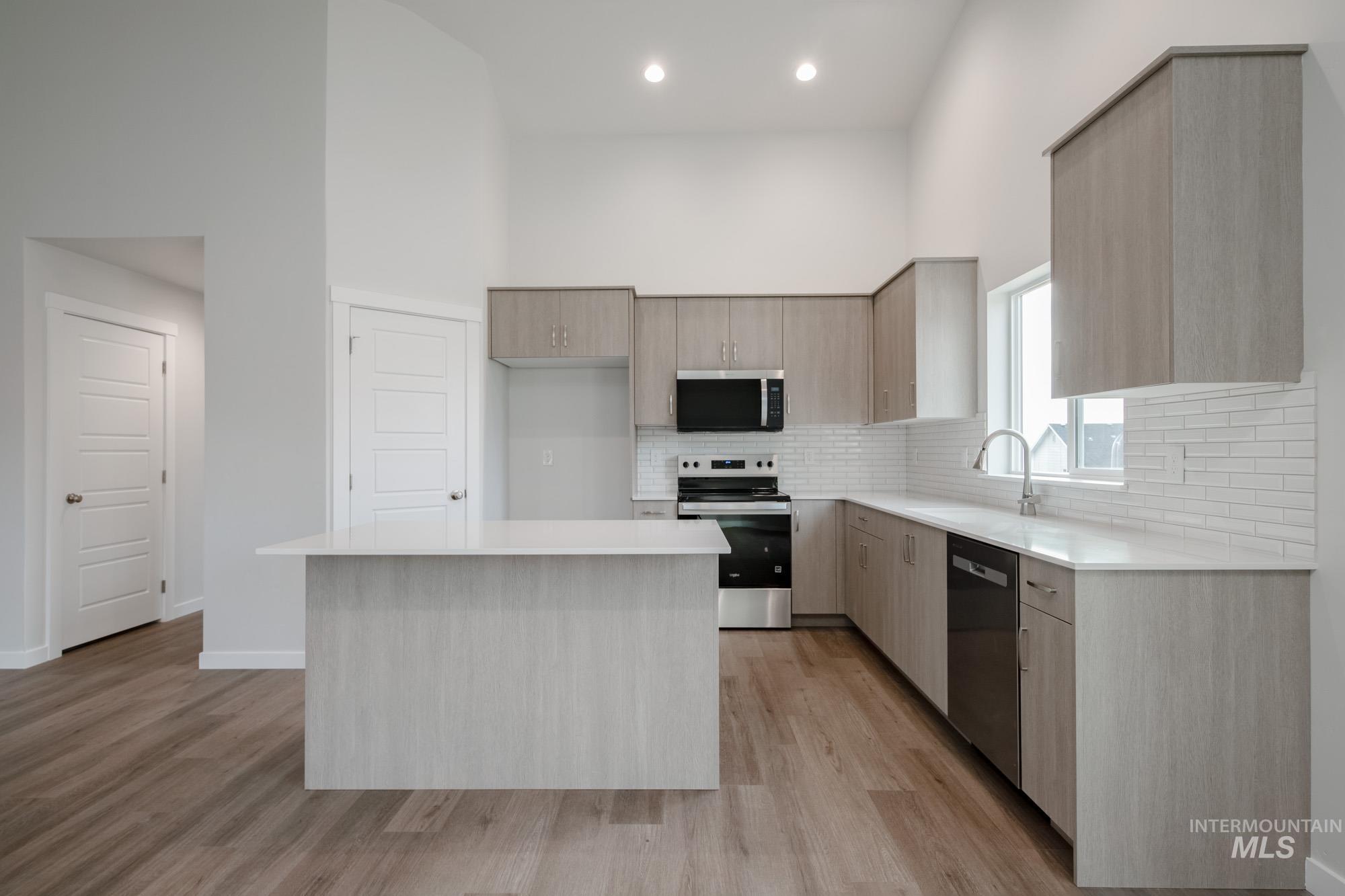 3281 North Waterbrook Way Star, ID 83669 - Photo 7 of 21 Kitchen featuring light brown cabinetry, stainless steel appliances, a center island, modern cabinets, and a towering ceiling