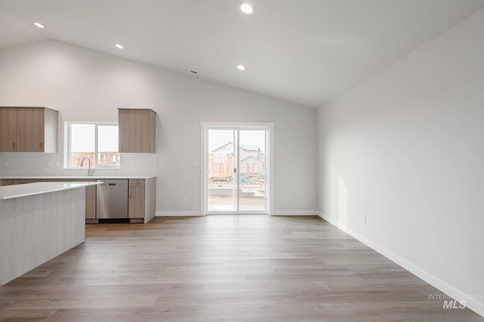 3281 North Waterbrook Way Star, ID 83669 - Photo 8 of 21 Kitchen featuring light wood-type flooring, lofted ceiling, healthy amount of natural light, backsplash, and recessed lighting