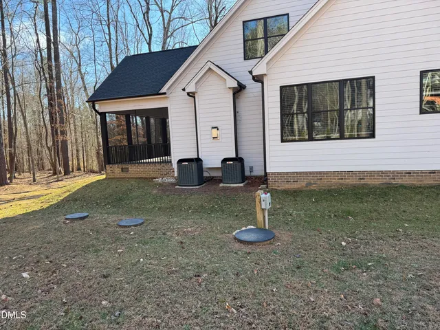 a view of a white house with a small yard and large tree