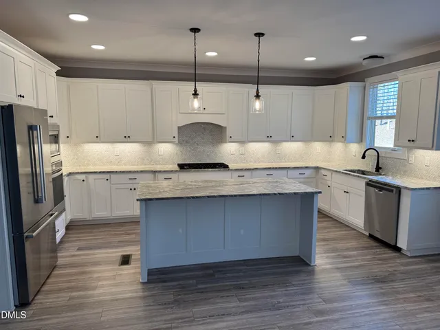 a kitchen with kitchen island granite countertop a sink a counter space stainless steel appliances and cabinets