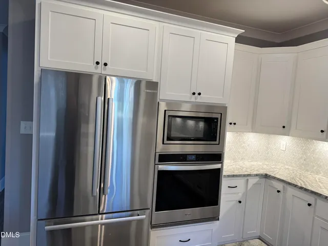 a kitchen with stainless steel appliances white cabinets and a refrigerator