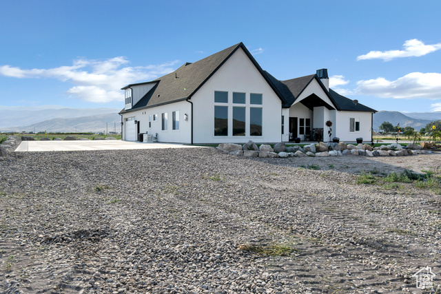 1952 Highway 118 Monroe, UT 84754 - Photo 10 of 88 Back of house featuring a mountain view, concrete driveway, a chimney, stucco siding, and an attached garage