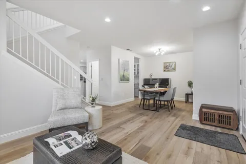 a living room with furniture and a dining table with wooden floor