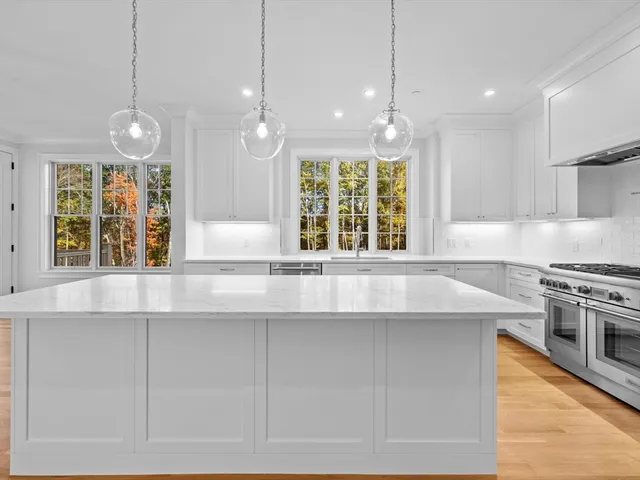 a kitchen with stainless steel appliances granite countertop a sink a stove and a large window