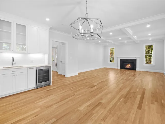 an empty room with wooden floor fireplace and windows