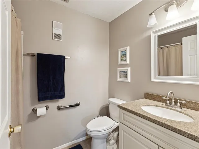 a bathroom with a granite countertop toilet sink and mirror