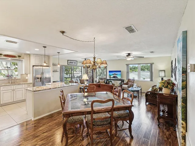 a view of a dining room and livingroom with furniture wooden floor a chandelier